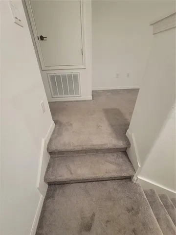 a view of staircase with white walls and door