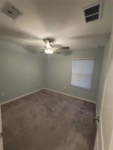 en empty room with windows and chandelier fan