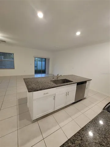 a kitchen with granite countertop a sink a counter top space and cabinets