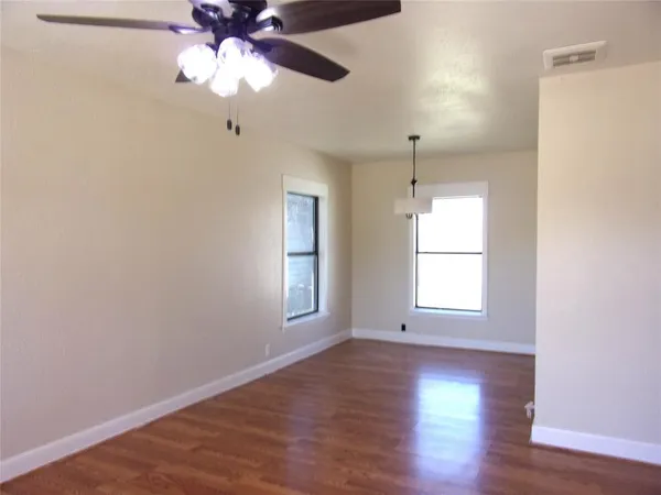 a view of an empty room with a window and wooden floor