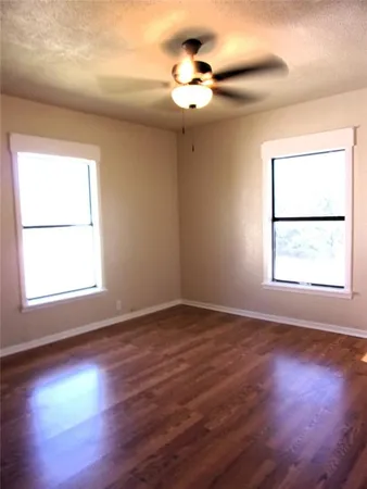 an empty room with wooden floor chandelier and windows