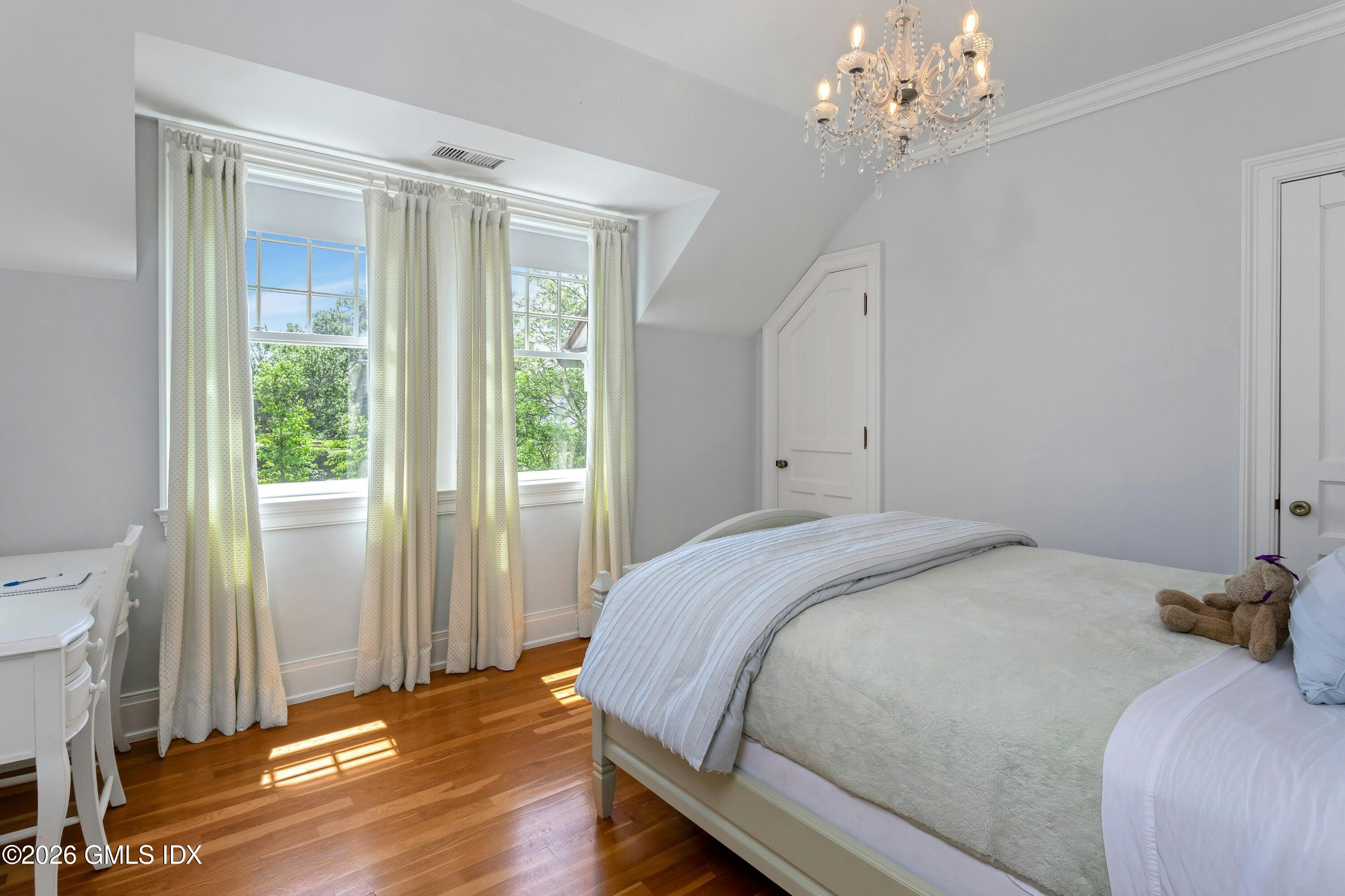 200 Shore Road Old Greenwich, CT 06870 - Photo 16 of 34 a bedroom with a bed chandelier and a window