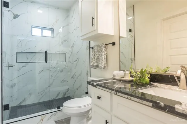 a bathroom with a granite countertop sink a toilet and shower