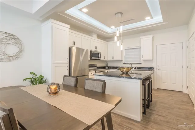 a kitchen with stainless steel appliances a dining table chairs and refrigerator