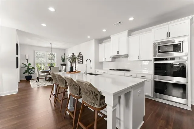 a dining room with stainless steel appliances kitchen island granite countertop a dining table chairs and a refrigerator
