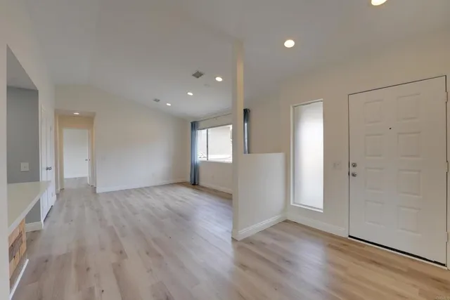 a view of empty room with wooden floor and window