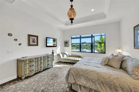 a spacious bedroom with a bed a dresser and a large window