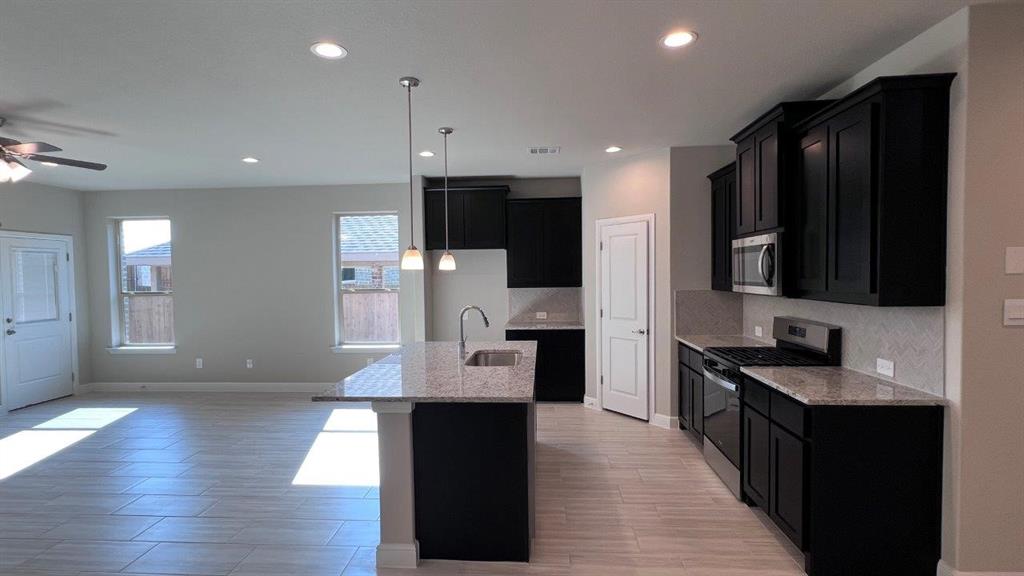 125 Medina Lane Rhome, TX 76078 - Photo 2 of 21 a kitchen with stainless steel appliances kitchen island granite countertop a refrigerator a sink and wooden floor