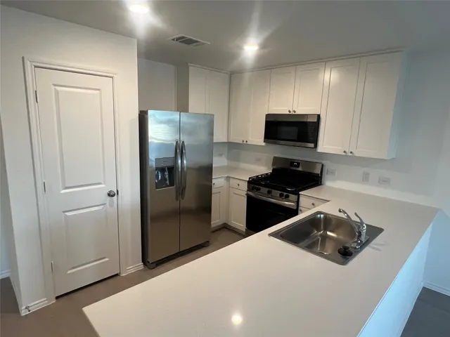 a kitchen with stainless steel appliances a refrigerator a sink a stove a microwave and cabinets