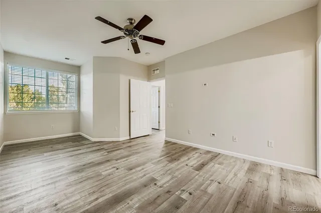 a view of empty room with wooden floor and fan