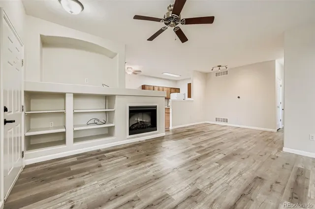 a view of empty room with wooden floor and fan