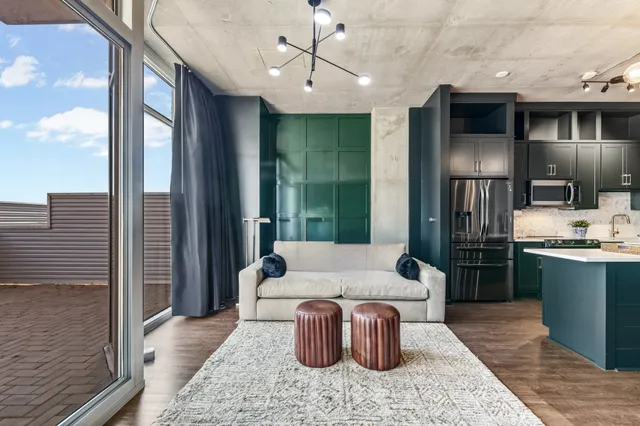 a living room with stainless steel appliances furniture a chandelier and a kitchen view