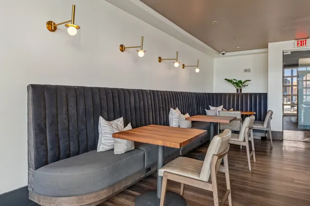 a living room with stainless steel appliances furniture a fireplace and a kitchen view