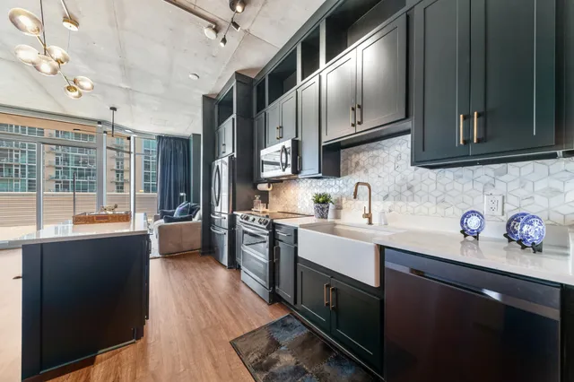 a kitchen with stainless steel appliances granite countertop a sink dishwasher stove and wooden cabinets