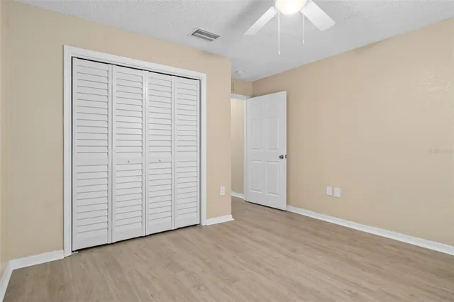 an empty room with wooden floor closet and windows