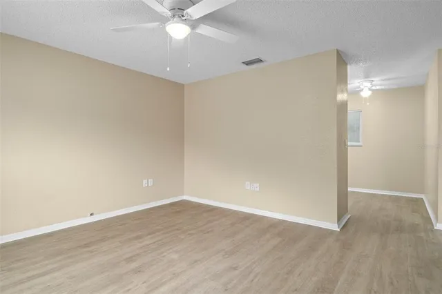 an empty room with wooden floor and fan