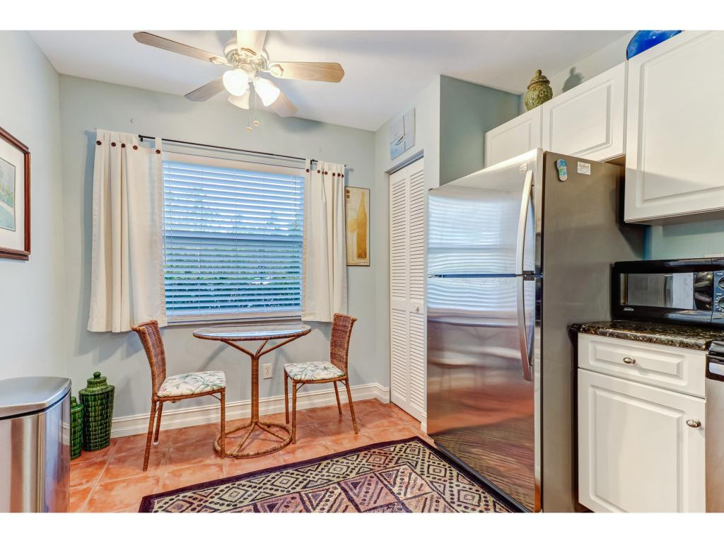 5739 Whitaker Road, Unit 103 Naples, FL 34112 - Photo 11 of 18 a kitchen with granite countertop a refrigerator cabinets and wooden floor
