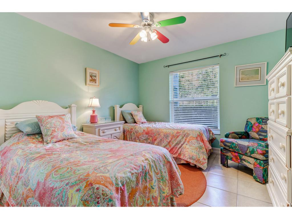 5739 Whitaker Road, Unit 103 Naples, FL 34112 - Photo 15 of 18 a bedroom with two beds and a chandelier