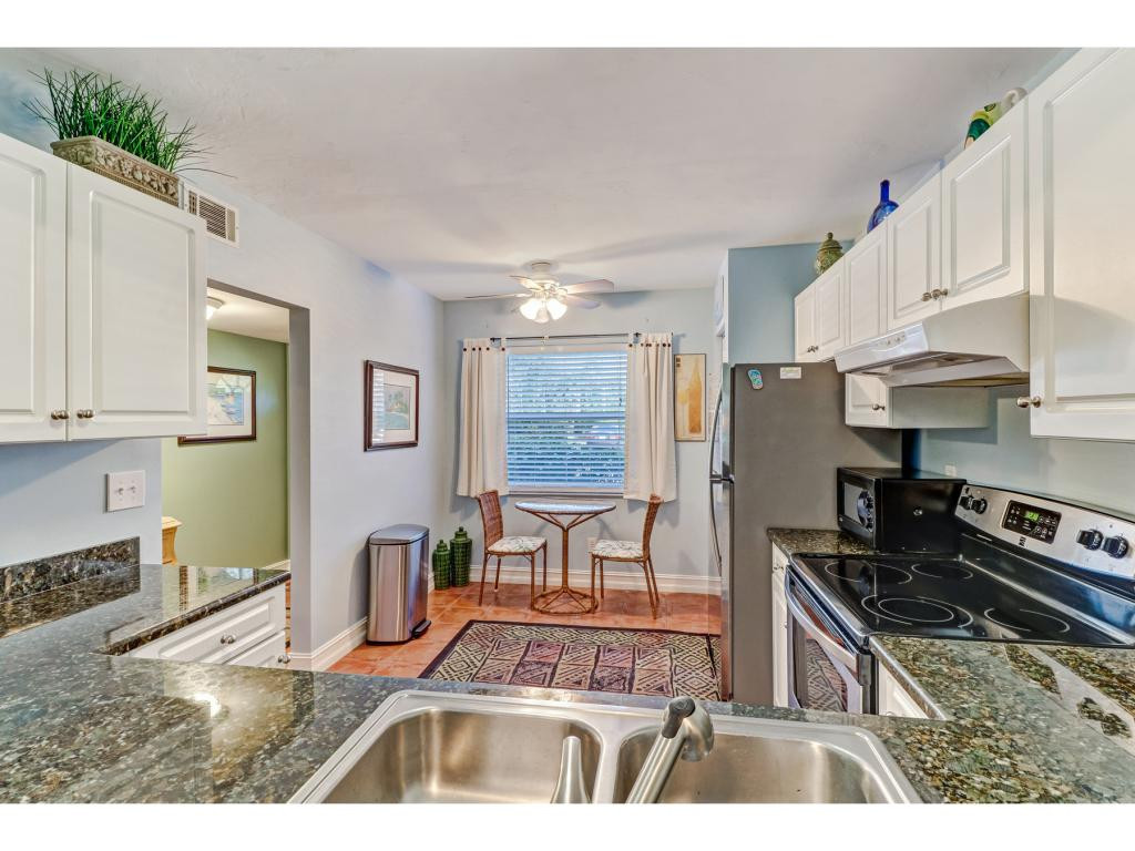 5739 Whitaker Road, Unit 103 Naples, FL 34112 - Photo 10 of 18 a kitchen with stainless steel appliances granite countertop a stove refrigerator and cabinets