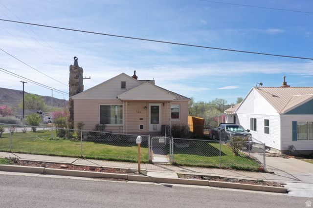 Bungalow-style house with a fenced front yard, a gate, and a chimney