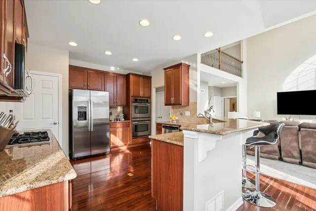 a kitchen with stainless steel appliances kitchen island granite countertop a refrigerator and a stove top oven