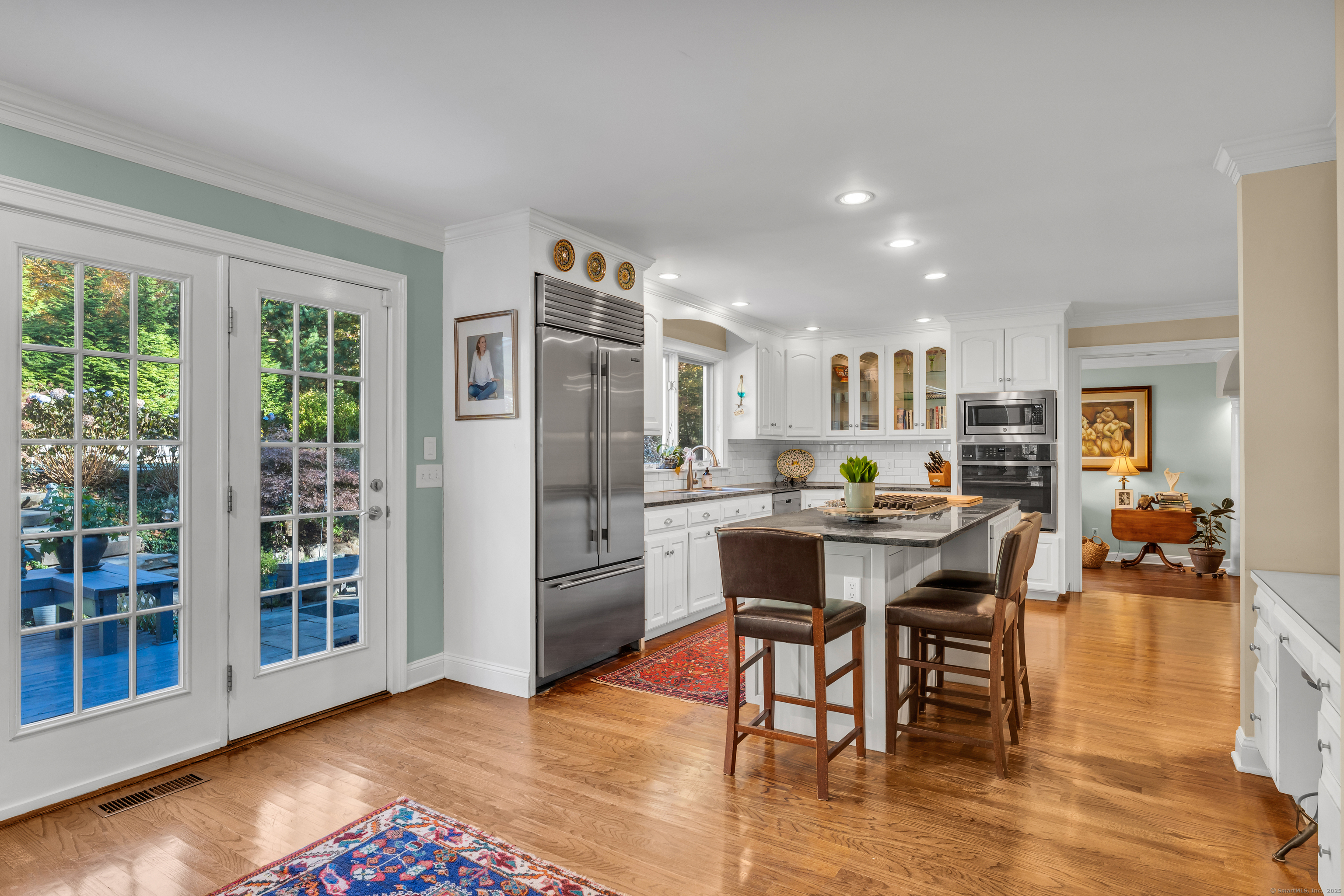 214 Nortontown Road Guilford, CT 06437 - Photo 11 of 40 a kitchen with stainless steel appliances kitchen island granite countertop a refrigerator a stove a dining table and chairs with wooden floor