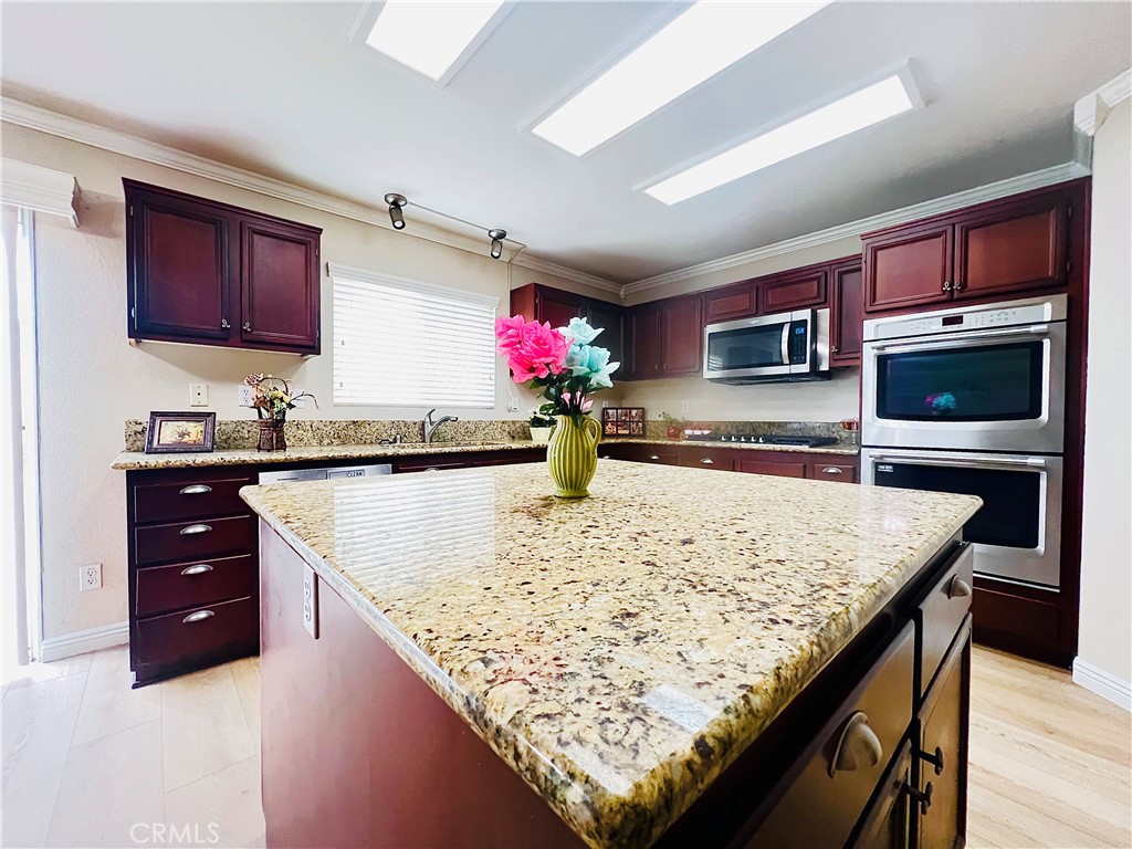 12270 Mesa Grove Drive Riverside, CA 92503 - Photo 11 of 41 a kitchen with stainless steel appliances kitchen island granite countertop wooden cabinets and granite counter tops