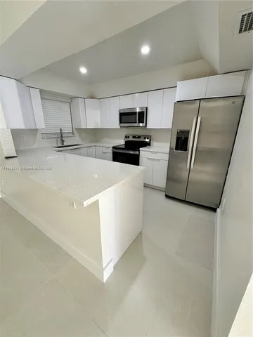 a large kitchen with a sink and stainless steel appliances