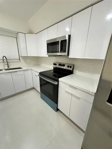 a kitchen with appliances a sink and cabinets