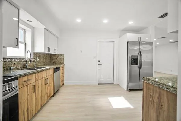 a kitchen with stainless steel appliances granite countertop a refrigerator and a sink