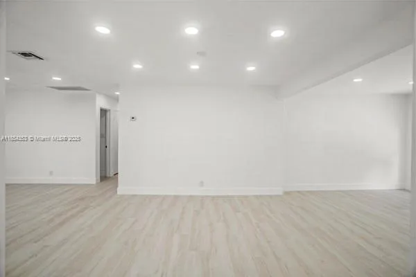 an empty room with wooden floor and natural light