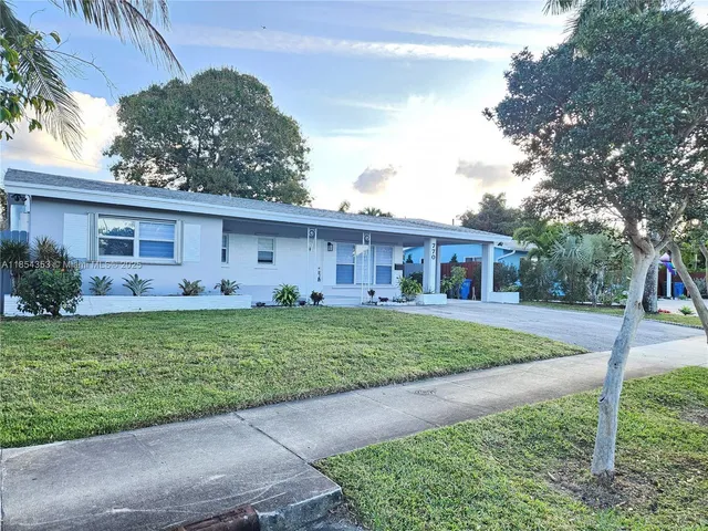 a view of a house with a yard and a large tree