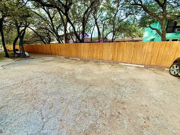 a view of swimming pool with large trees and wooden fence