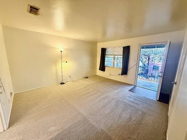 a view of an empty room with a fireplace and a window