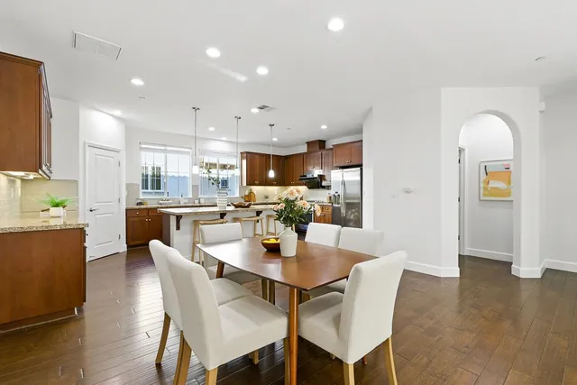 a dining room with stainless steel appliances kitchen island granite countertop a dining table chairs and a refrigerator