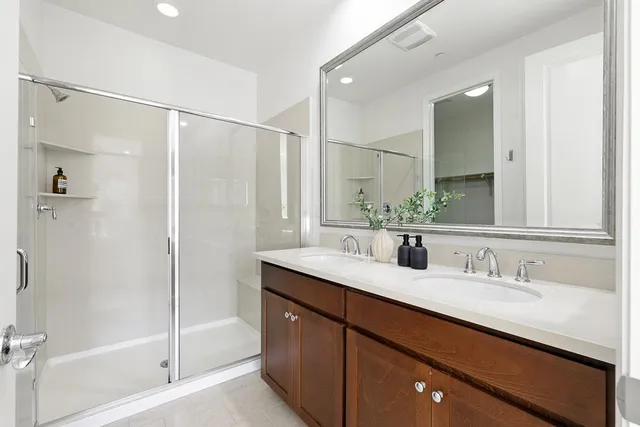 a bathroom with a double vanity sink mirror and shower