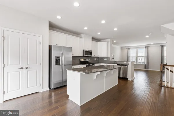 a large kitchen with stainless steel appliances granite countertop a large center island and a refrigerator