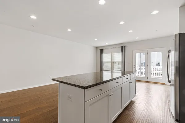 a large kitchen with stainless steel appliances granite countertop a large counter top and a wooden floor