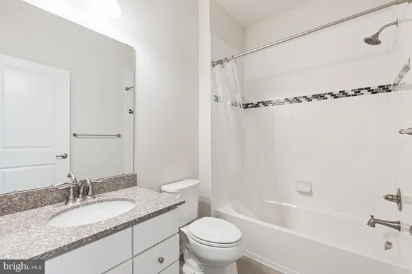 a bathroom with a granite countertop sink toilet mirror vanity and bathtub