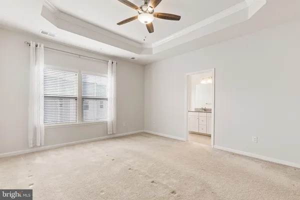 an empty room with chandelier fan and windows