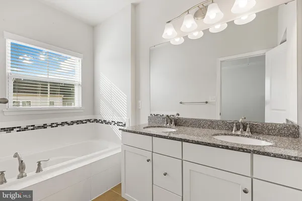 a bathroom with a granite countertop sink a large mirror and a bathtub