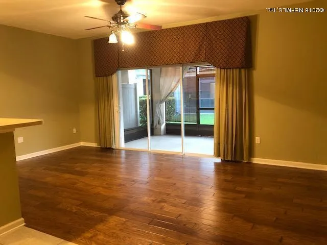 a view of an empty room with window and wooden floor