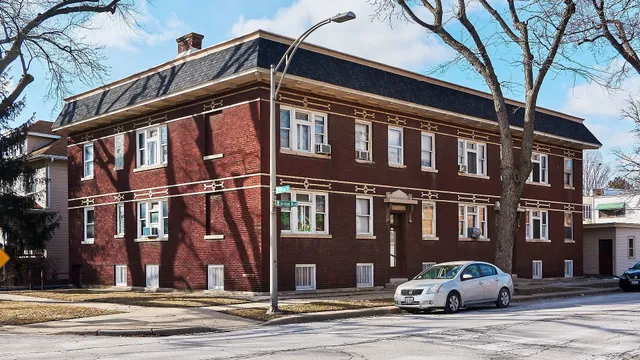 a front view of a building with lot of cars and trees