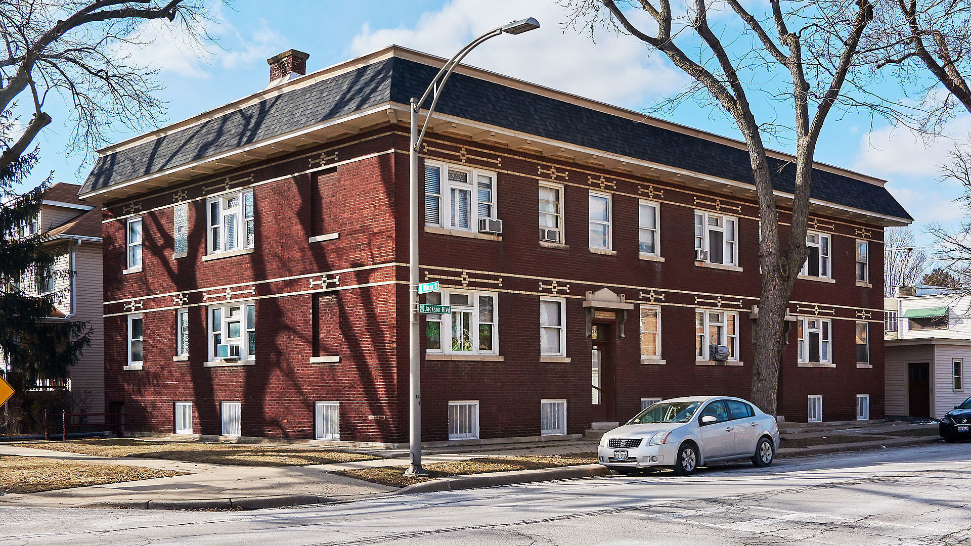 a front view of a building with lot of cars and trees
