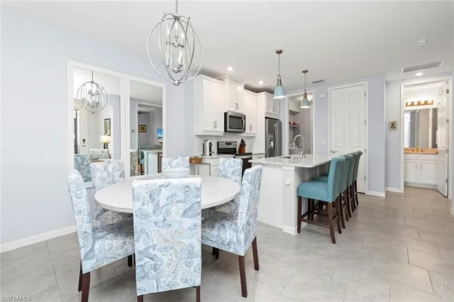 a kitchen with stainless steel appliances a table chairs refrigerator and microwave