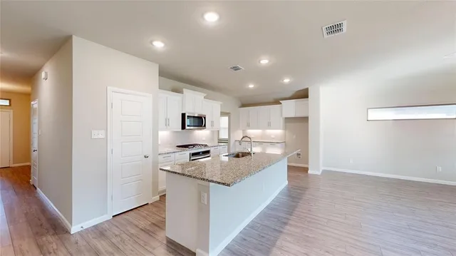 a large kitchen with stainless steel appliances a sink a stove a refrigerator and cabinets