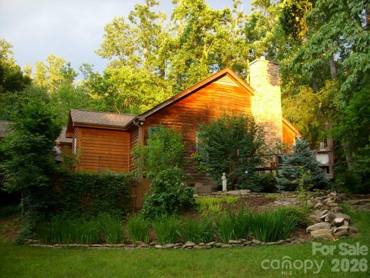 341 Sugar Hollow Road Fairview, NC 28730 - Photo 2 of 24 a backyard of a house with plants and large trees