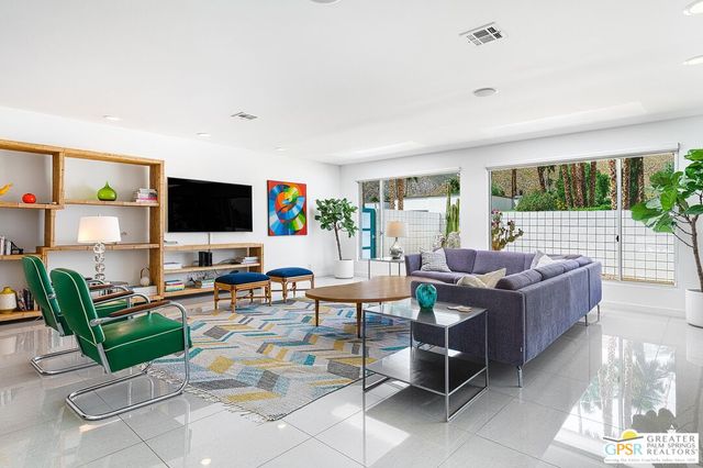 a living room with furniture a flat screen tv and a floor to ceiling window