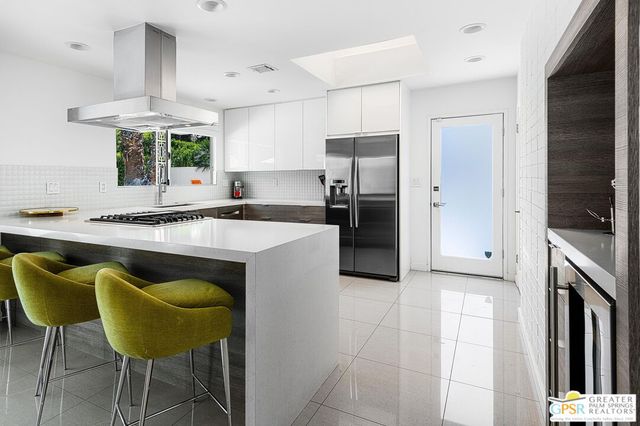 a kitchen with stainless steel appliances granite countertop a sink a stove a refrigerator and island