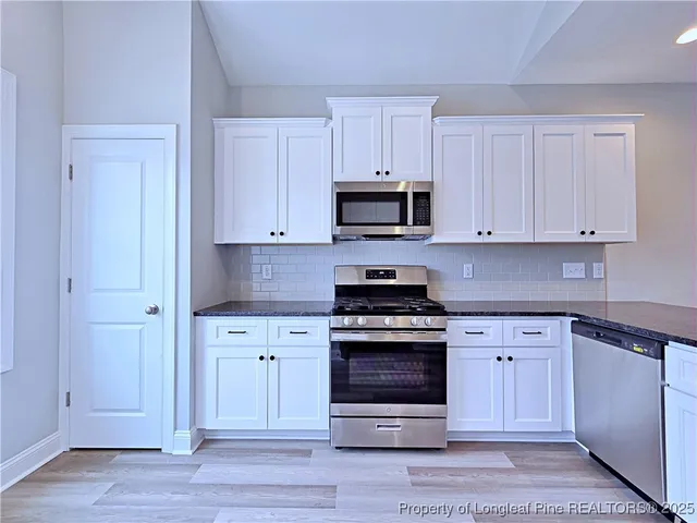 a kitchen with cabinets stainless steel appliances a sink and a stove